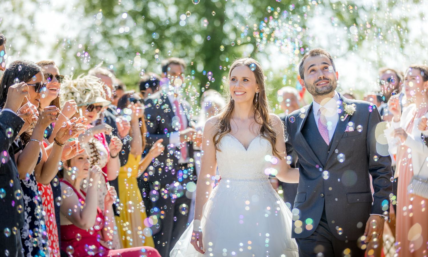 Wedding guests shower newlyweds with white confetti petals during outdoor celebration exit.