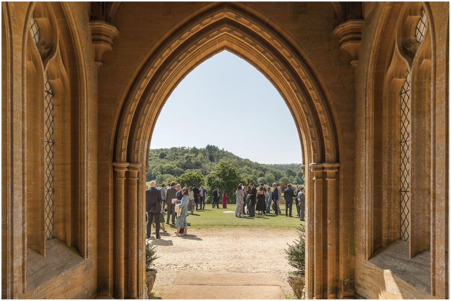 Stone archways frame a scenic countryside view through church windows.