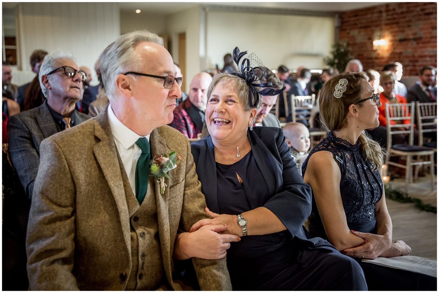 Wedding guests mingling and celebrating in brick-walled reception venue.