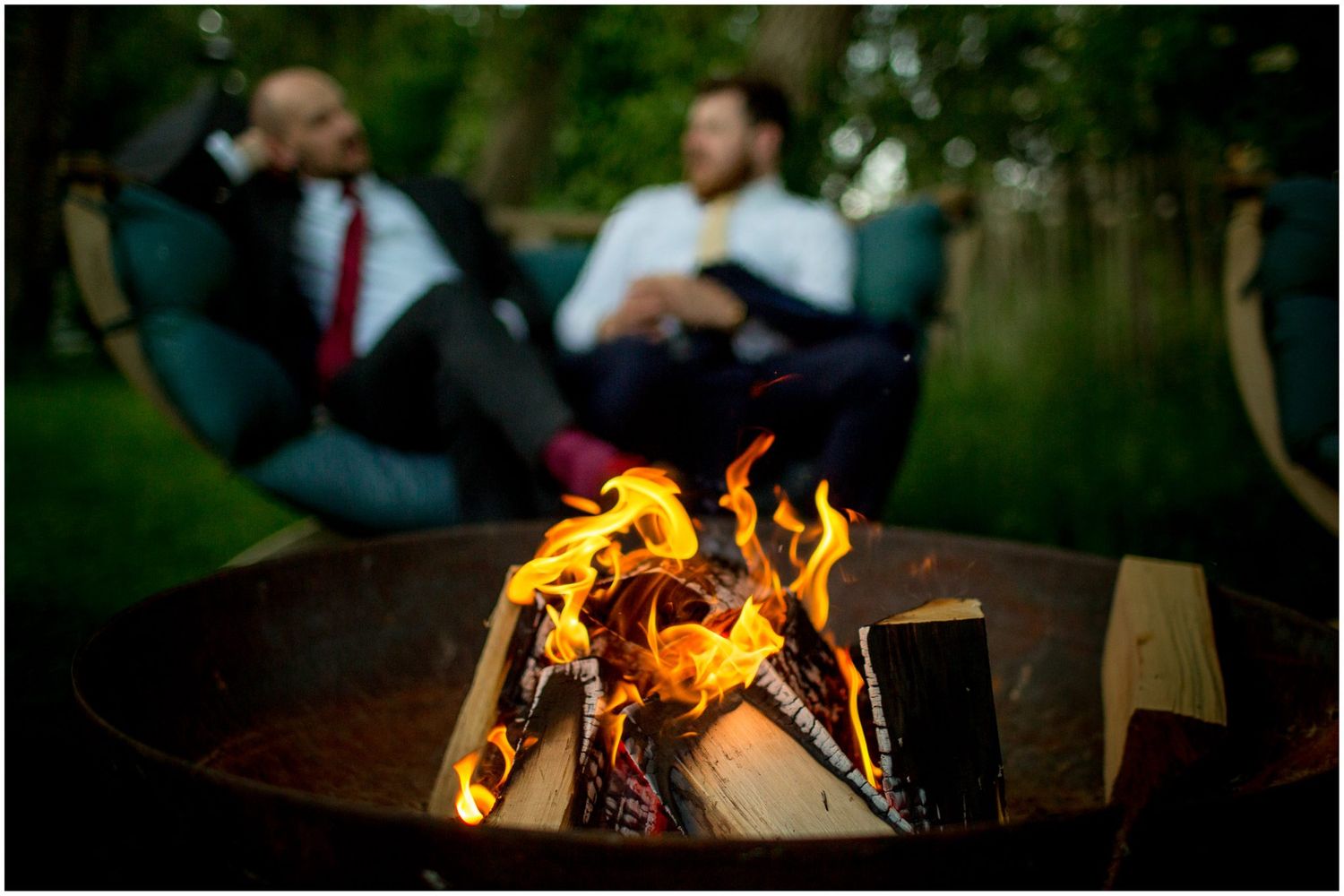 Outdoor wedding celebration with cozy bonfire and warm evening atmosphere.