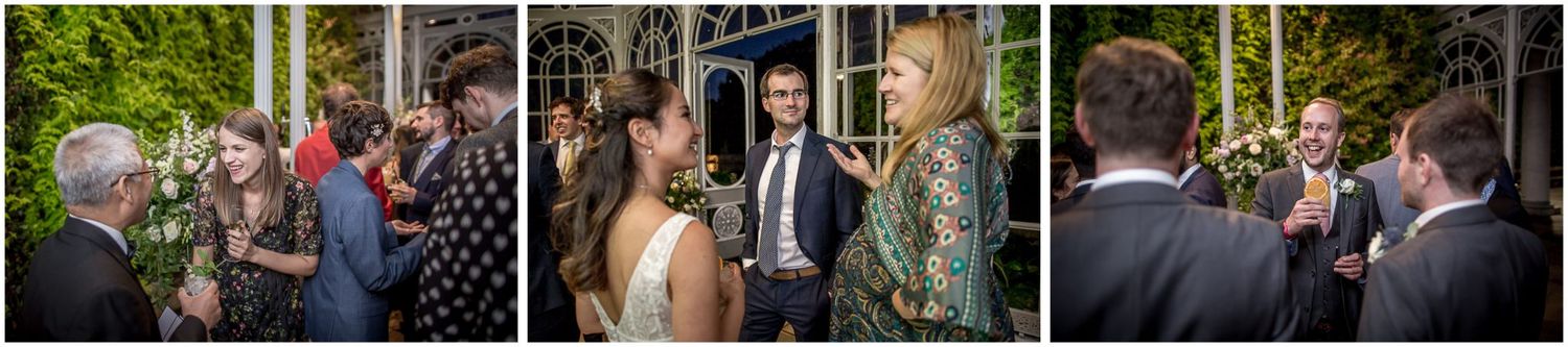 Wedding guests mingle during outdoor cocktail reception on mansion grounds.