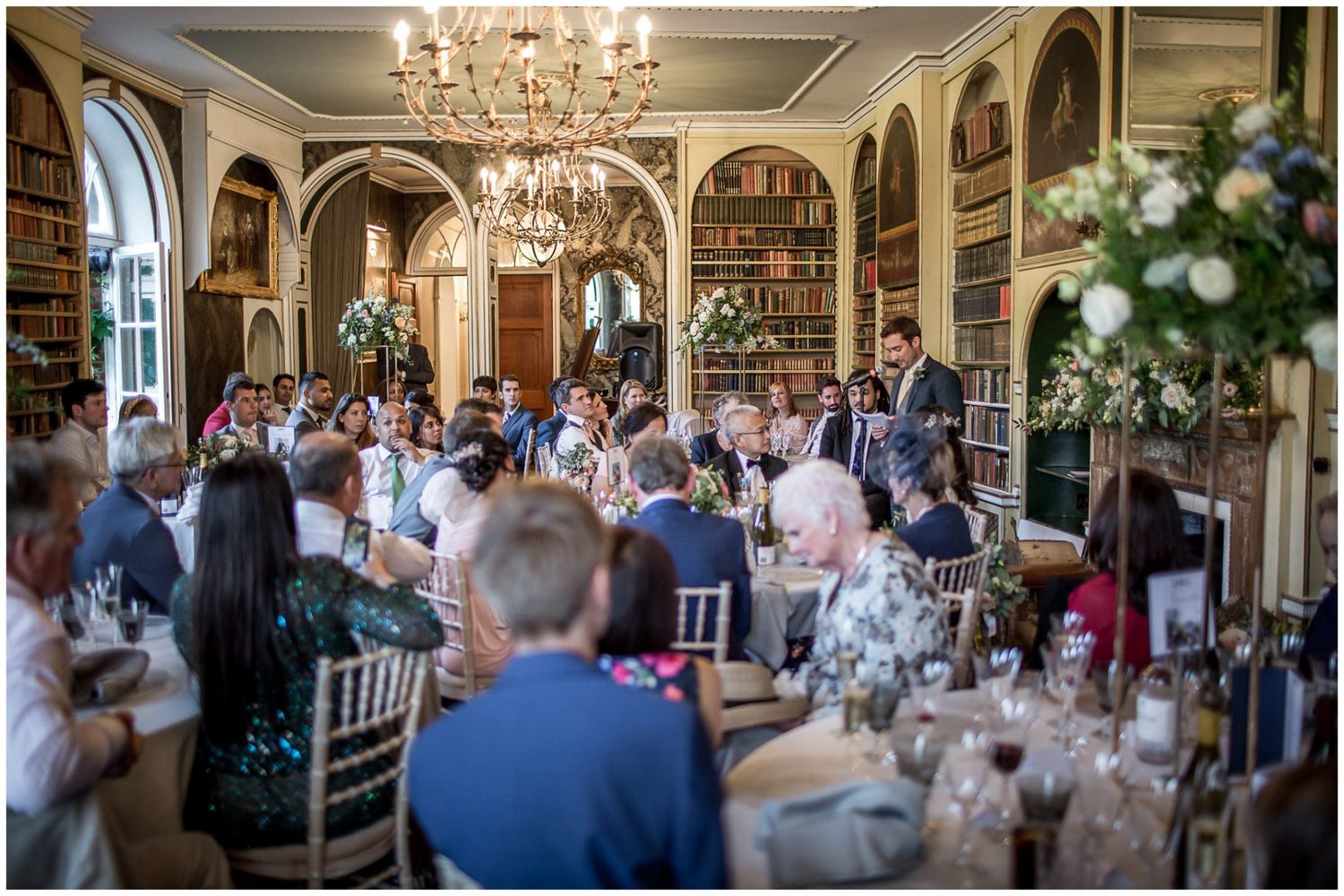 Elegant wedding reception hall decorated with chandeliers and white floral arrangements.