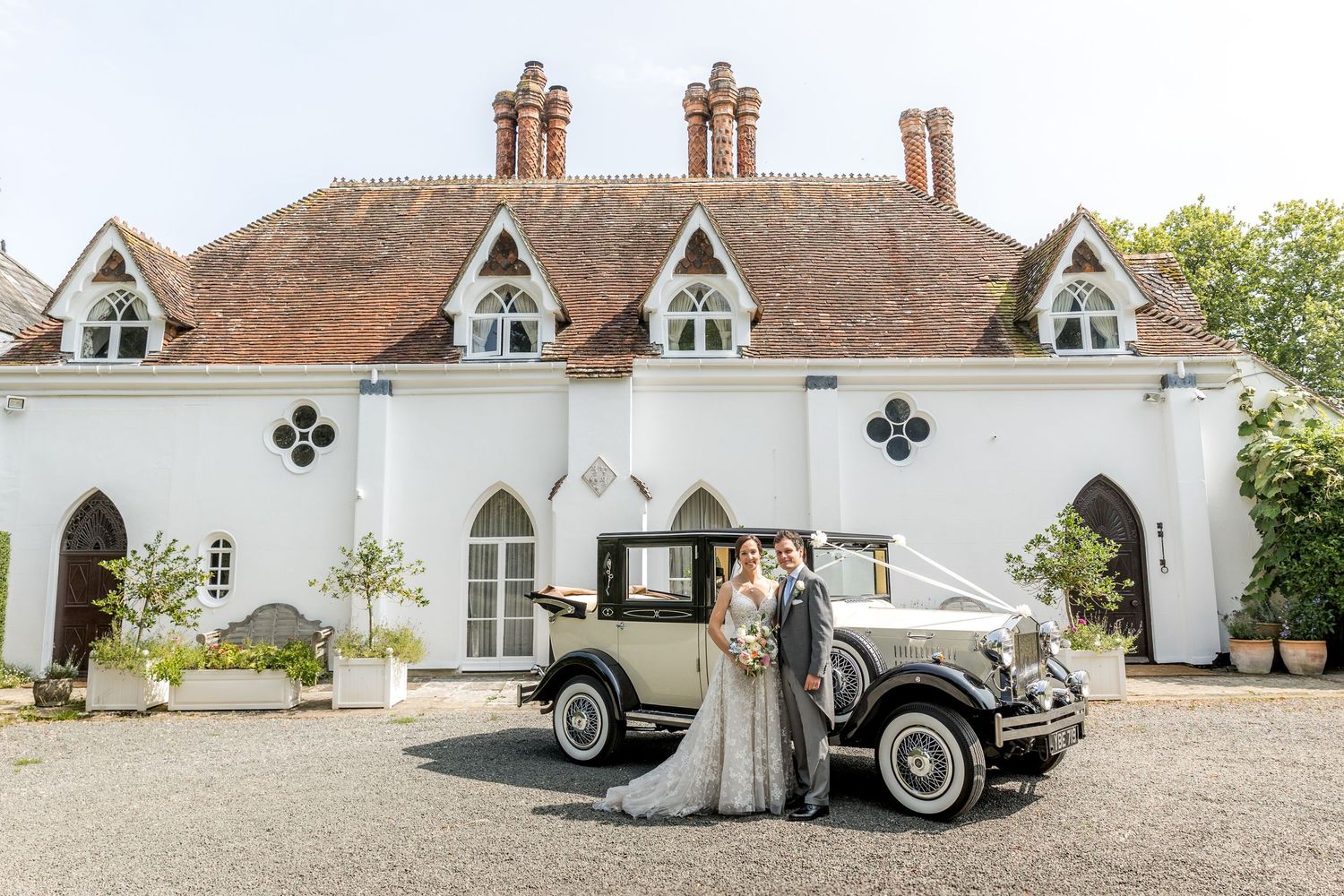 Bride and groom pose with their wedding car outside Houghton Lodge, a Hampshire wedding venue.