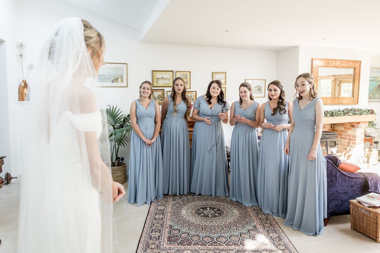 Bridesmaids in matching blue dresses line up while looking at the bride.