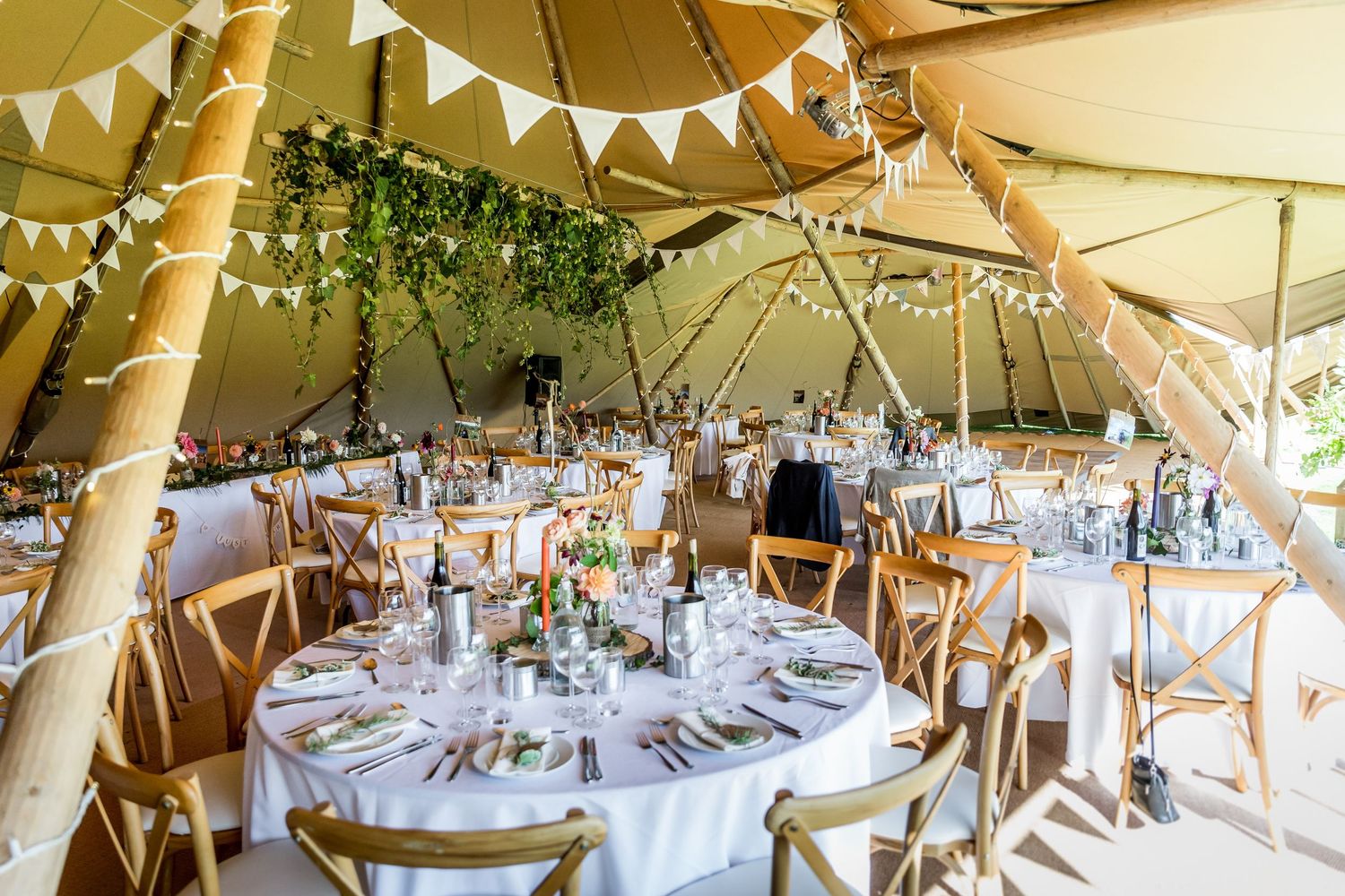 Wedding reception tent decorated with white bunting and fairy lights.