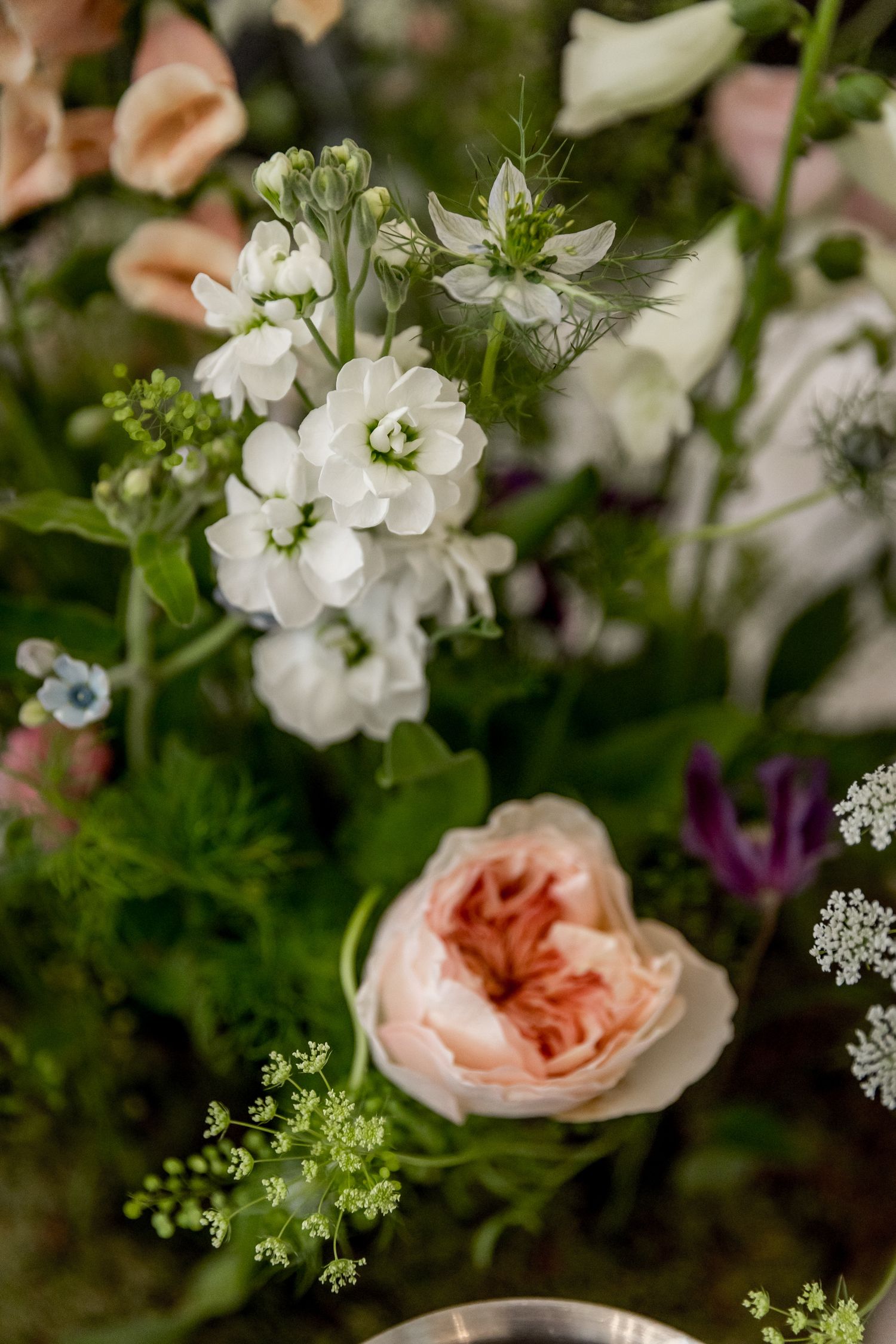 Close-up of delicate white and peach floral arrangements with greenery.