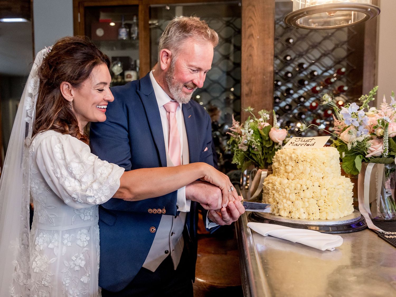 Newlyweds sharing a moment while cutting their wedding cake together.