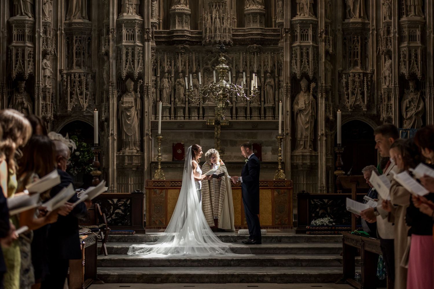 Gothic cathedral interior with ornate wooden details and vaulted ceiling during ceremony.