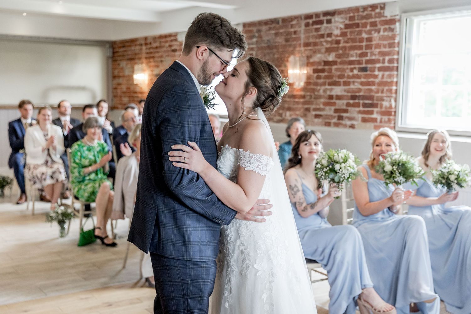 Wedding party gathered in an industrial-style venue with exposed brick walls and natural lighting.