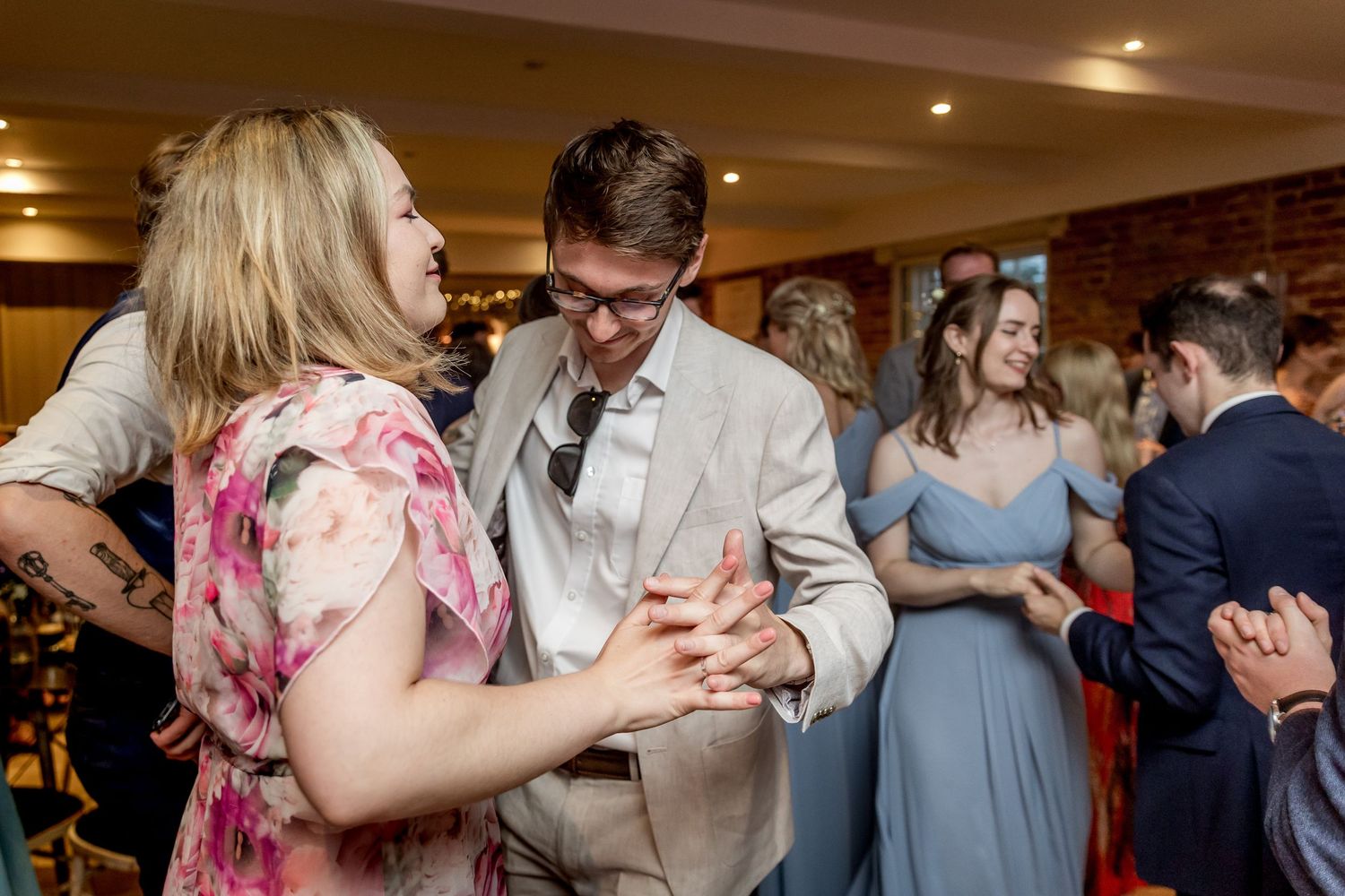 Couples dancing and having fun at a wedding reception with exposed brick walls.