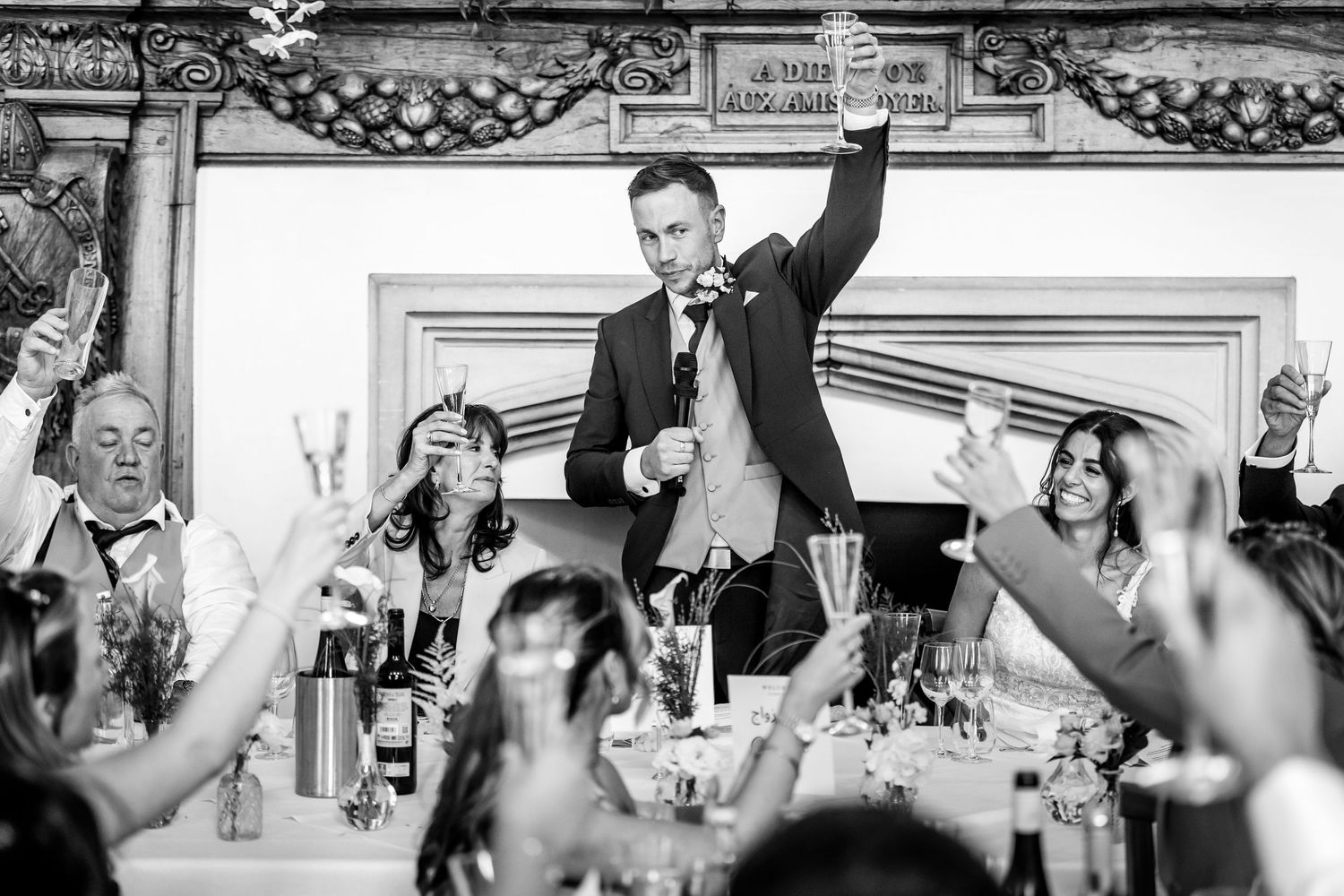 Wedding guests raise their hands in celebration during a reception party at an elegant indoor venue.