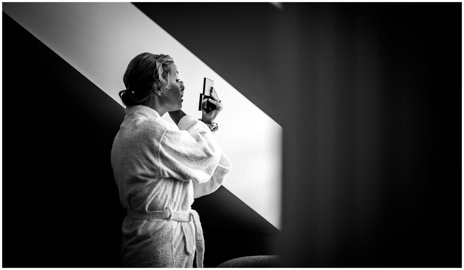 A dramatic black and white photo shows a person in a white robe standing in a beam of light while holding a gun.