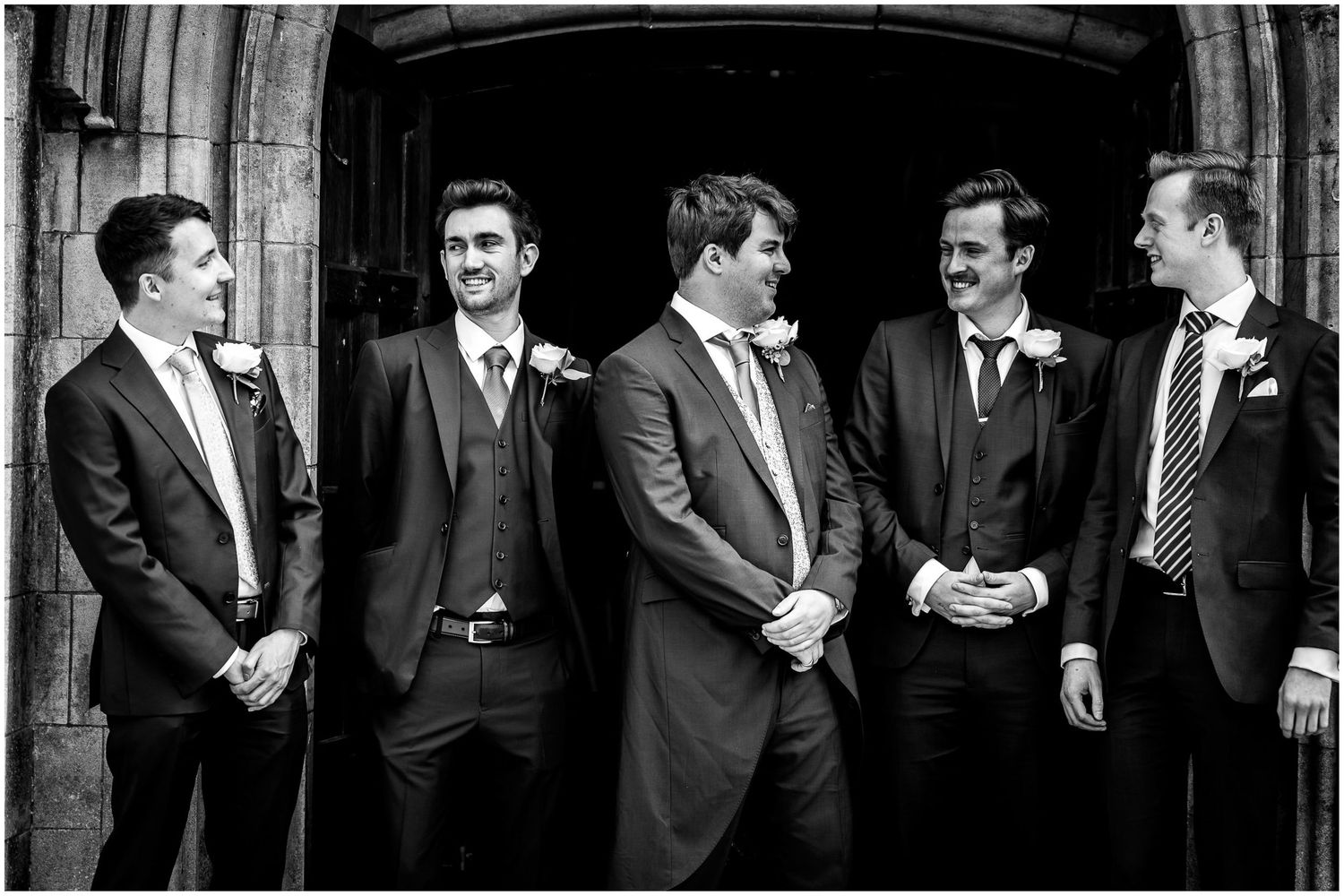 A group in formal attire laughs together inside a historic church setting.