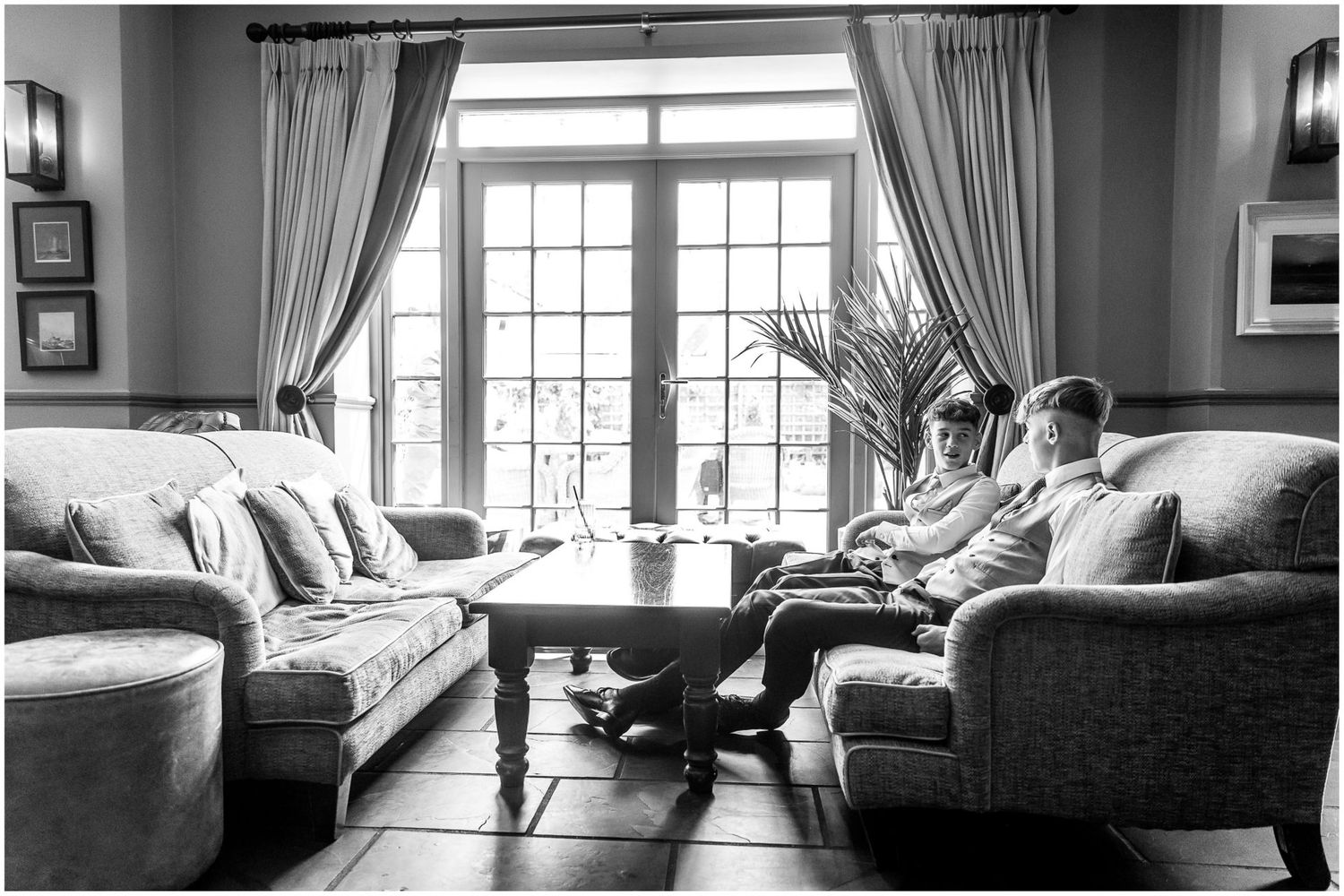 Black and white panoramic views of an elegant room with large windows and classic furniture.