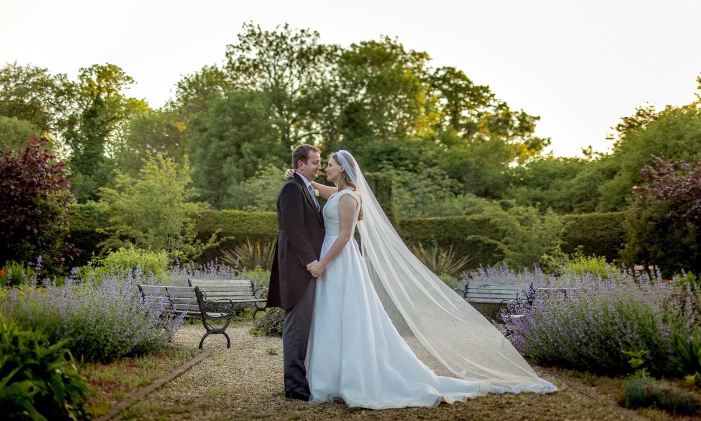 Newlyweds posing for romantic sunset portraits in a garden setting.