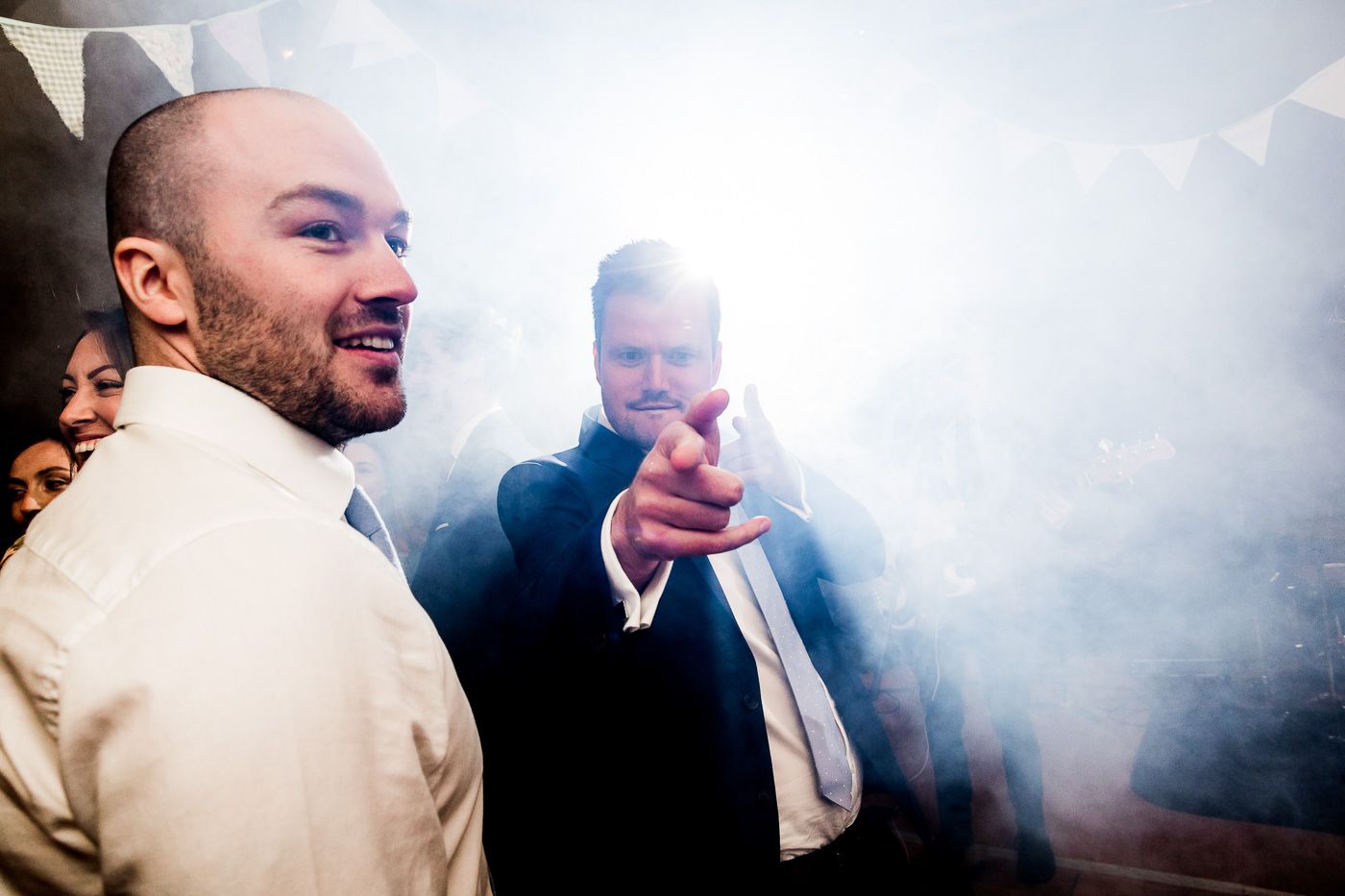 Two guests enjoying a festive moment with smoke effects at a wedding reception.