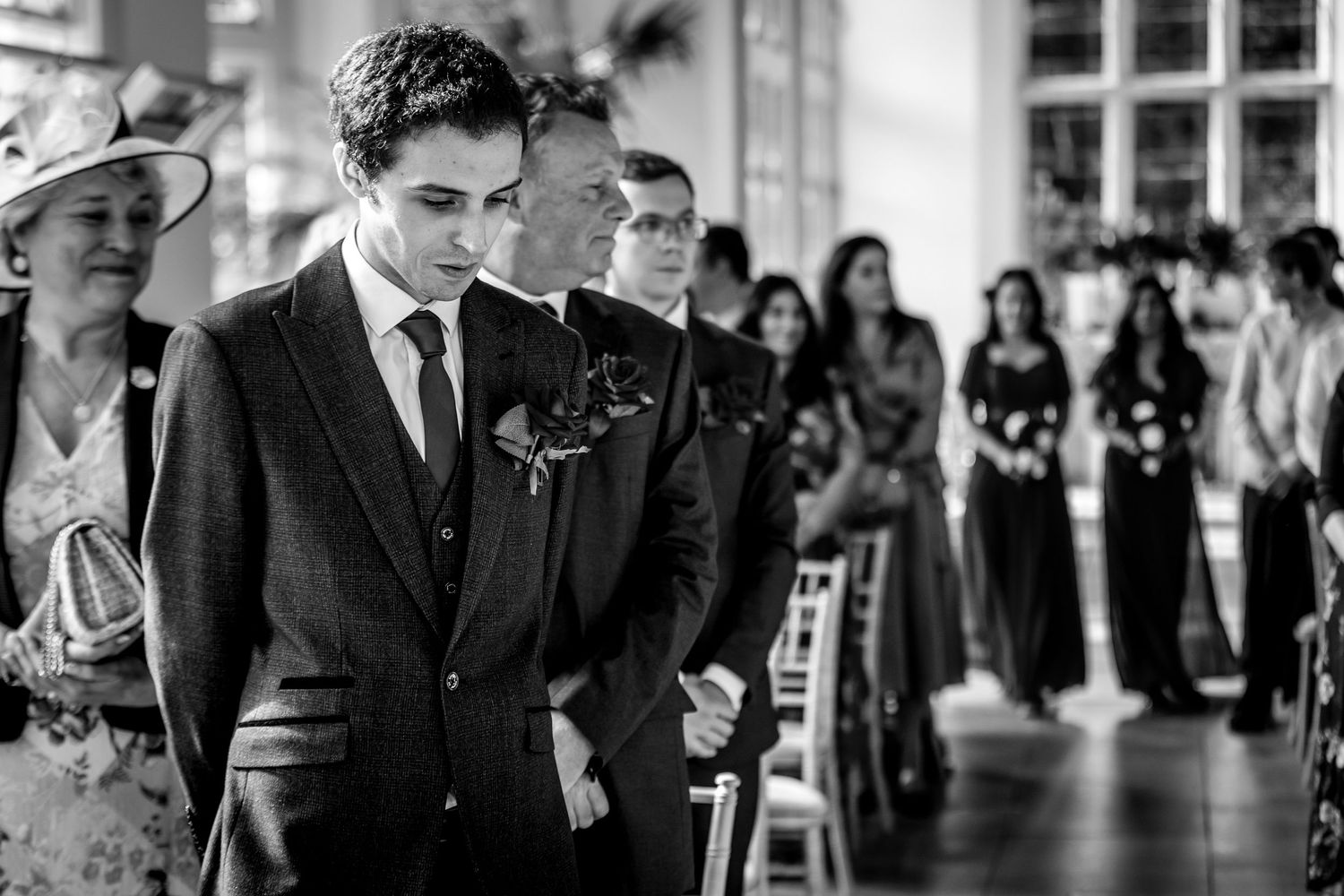 Indoor wedding ceremony with guests seated in elegant venue with natural light.