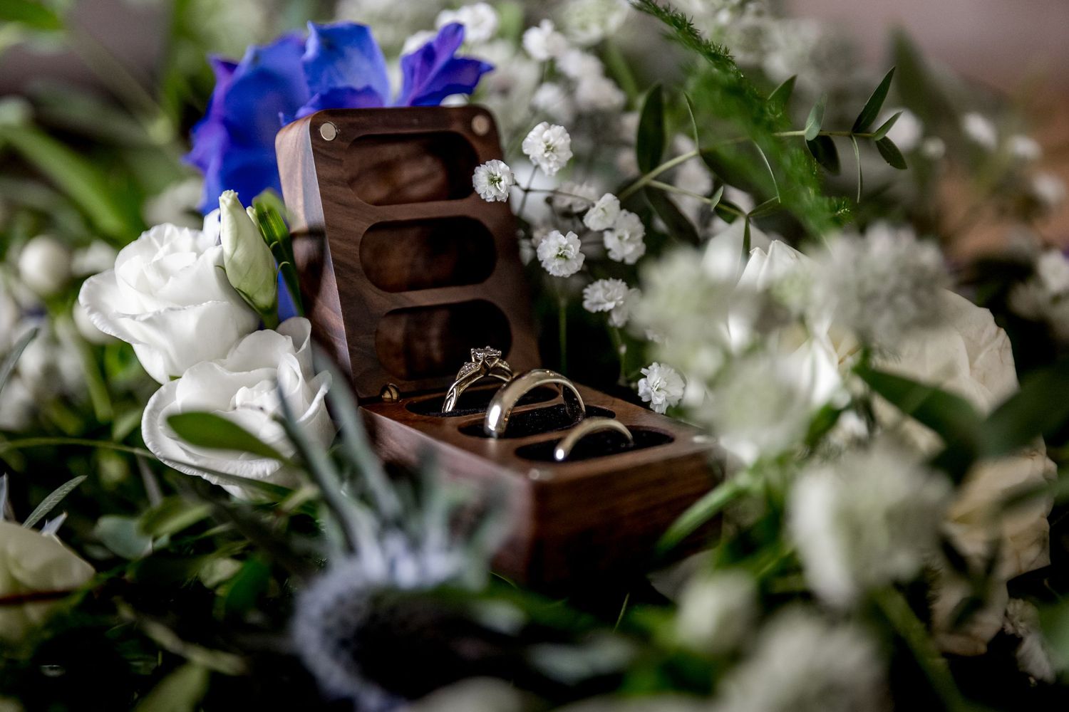 Wedding rings nestled among white flowers and crystal decorations with blue accents.