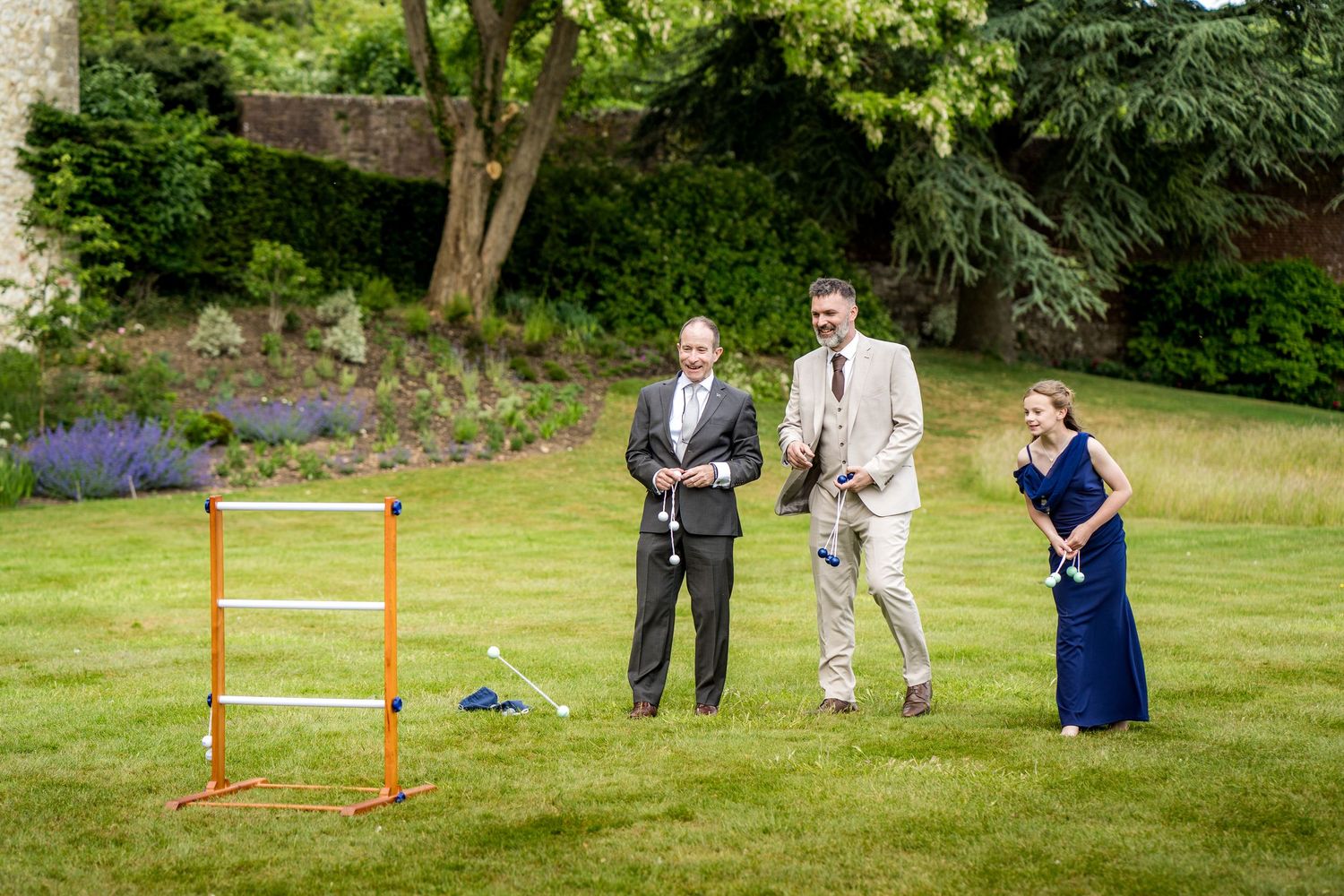Guests playing lawn games at a wedding reception in a lush garden setting.