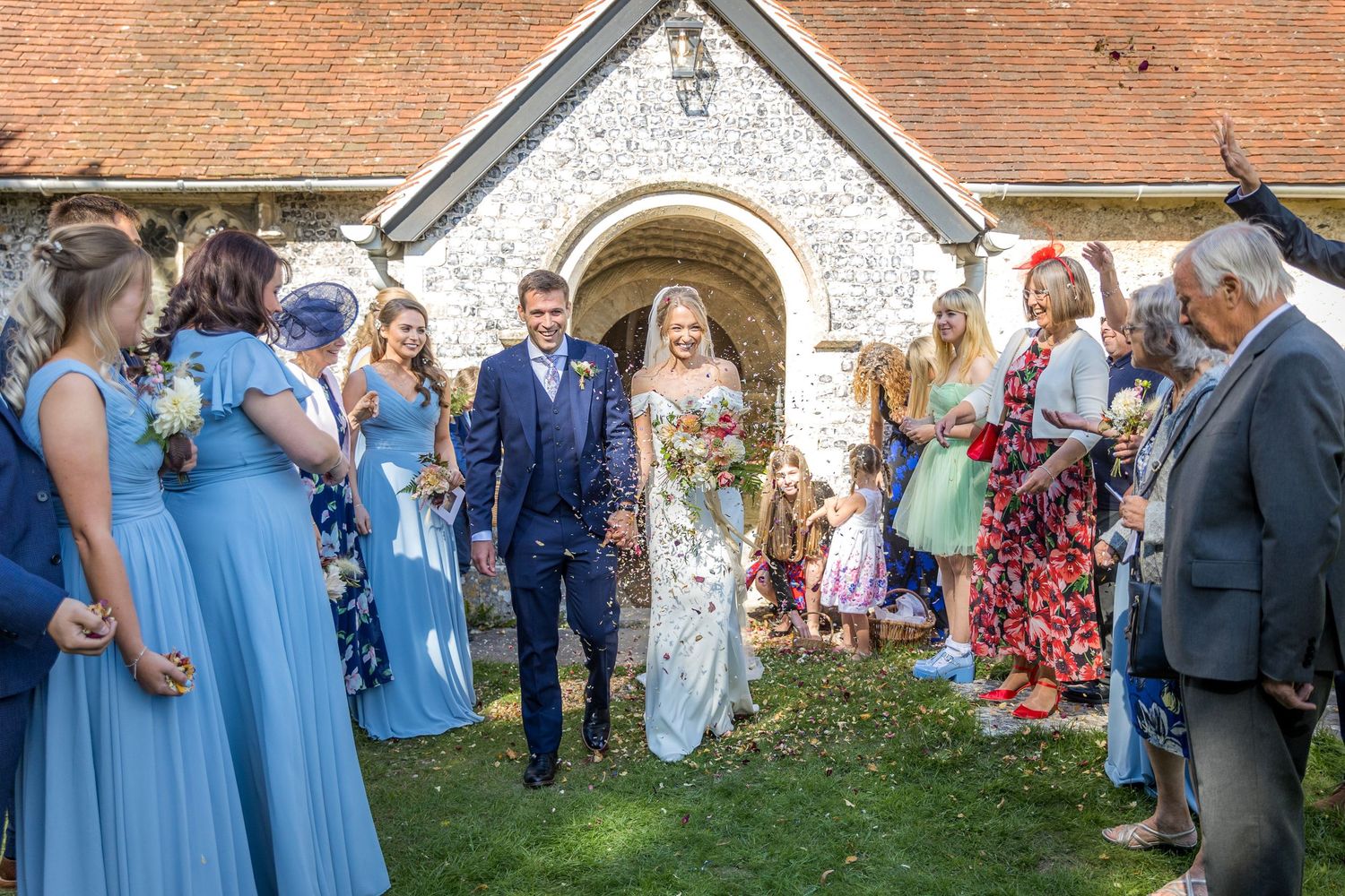 Wedding guests gather outside a historic brick church during an outdoor celebration.