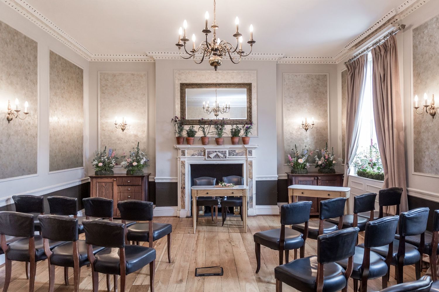 Elegant dining room with crystal chandelier, white walls, and navy blue upholstered chairs.