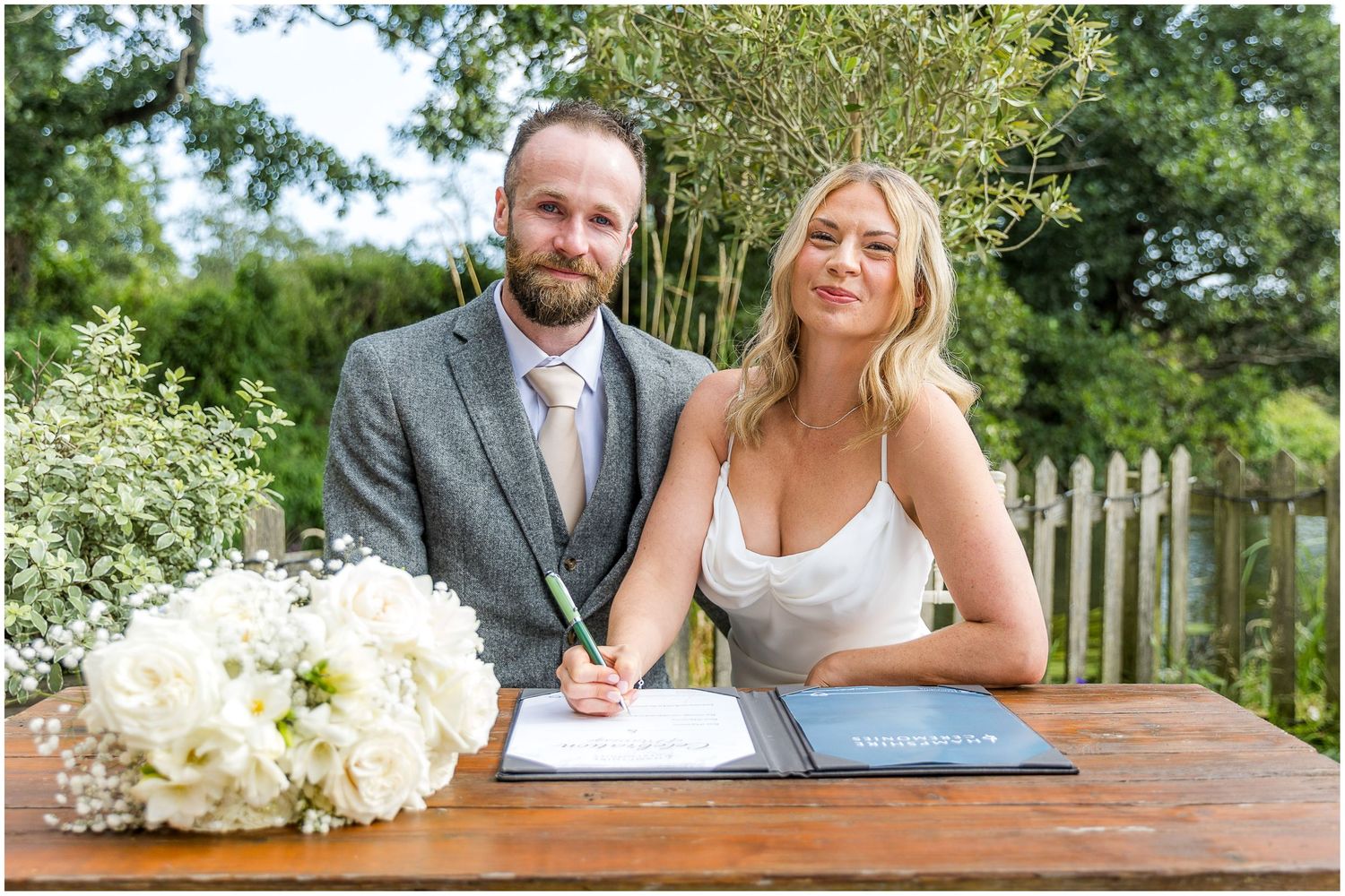Wedding couple and guests celebrate at a scenic outdoor venue with white floral decorations.
