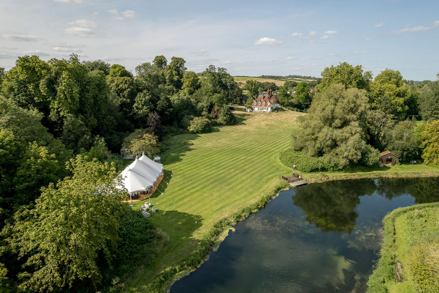 Aerial panoramic view of a wedding venue with lush green grounds and winding river.