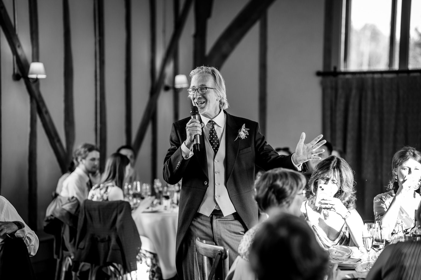 Wedding reception venue with guests celebrating at decorated tables under ambient lighting.