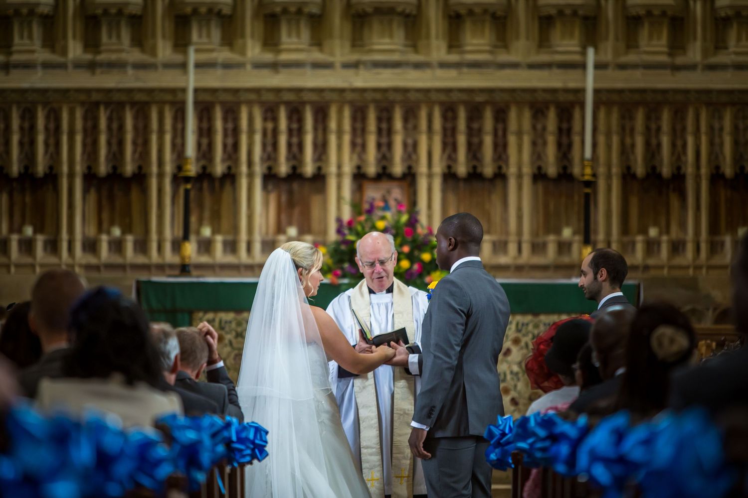 Wedding photography in Dorset as a bride and groom hold hands in the Abbey at Milton Abbey School and make their marriage vows