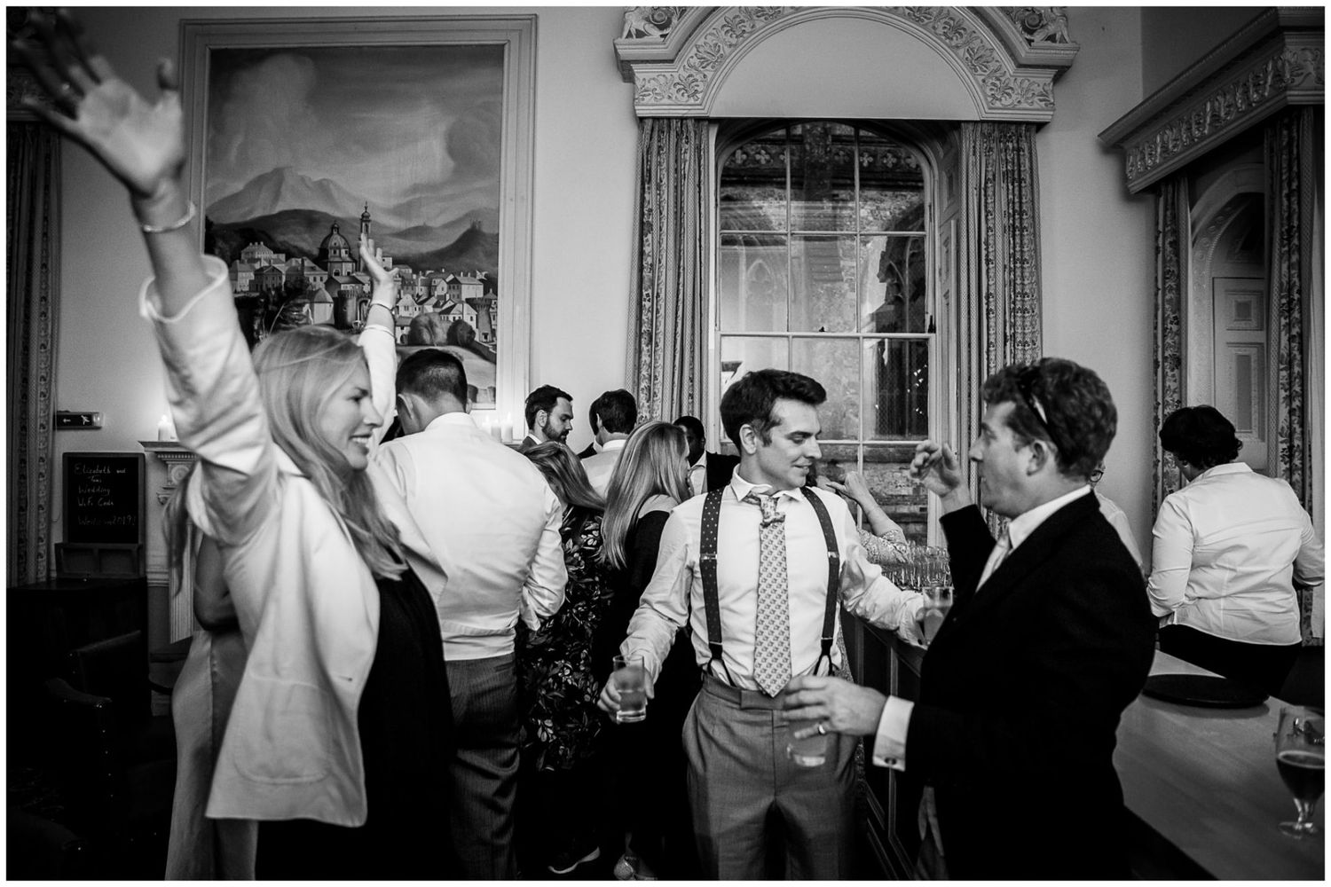 Black and white photo series showing a wedding reception with dancing guests and formal attire in an elegant venue.