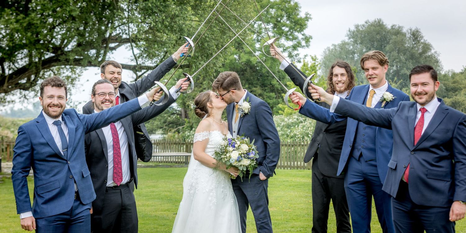 Celebratory group photo of wedding party members cheering outdoors.