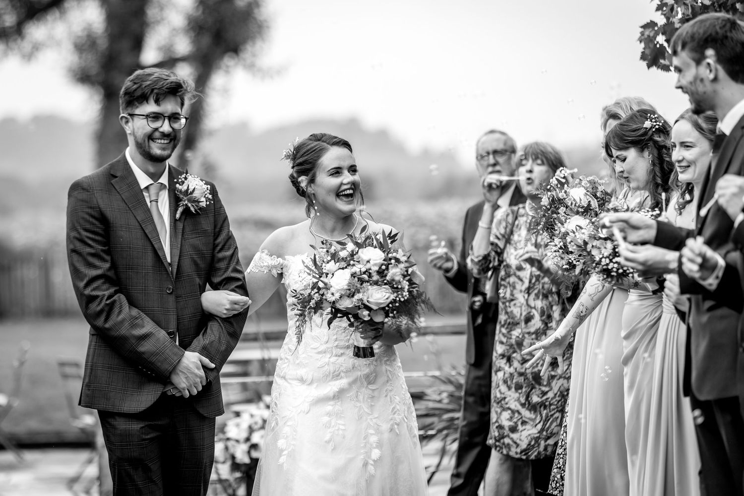 Wedding guests gather outdoors for a joyful celebration with natural scenery in the background.