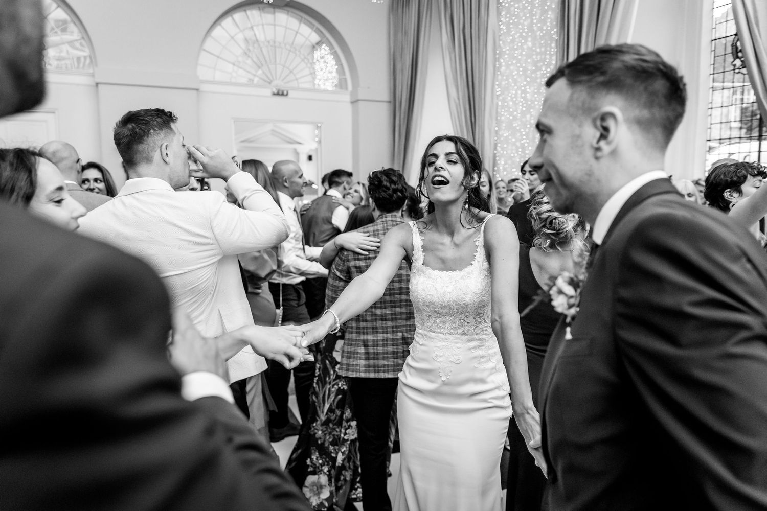 Wedding guests dancing and celebrating together on a checkered dance floor at an elegant reception venue.