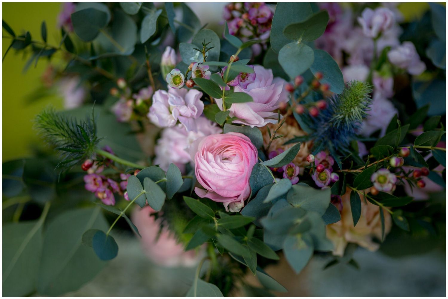 Elegant floral arrangements with pink roses and greenery decorate a wedding reception venue.