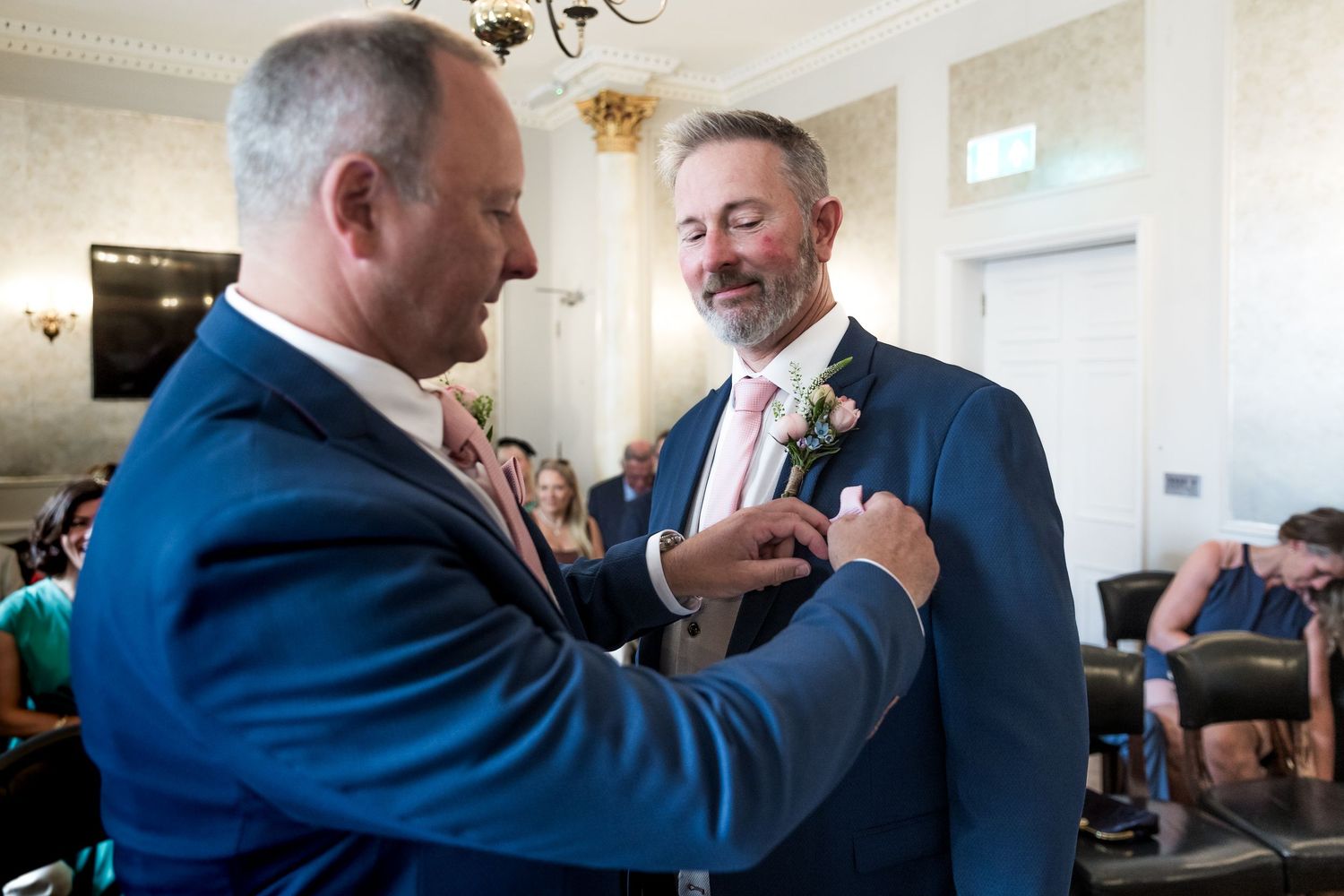Men in formal attire interact during a wedding celebration.