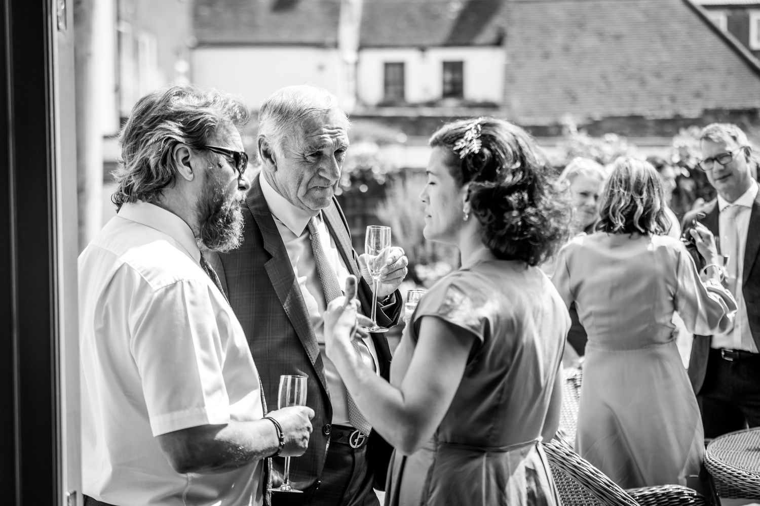 Black and white photo of guests mingling and chatting at an outdoor social gathering.