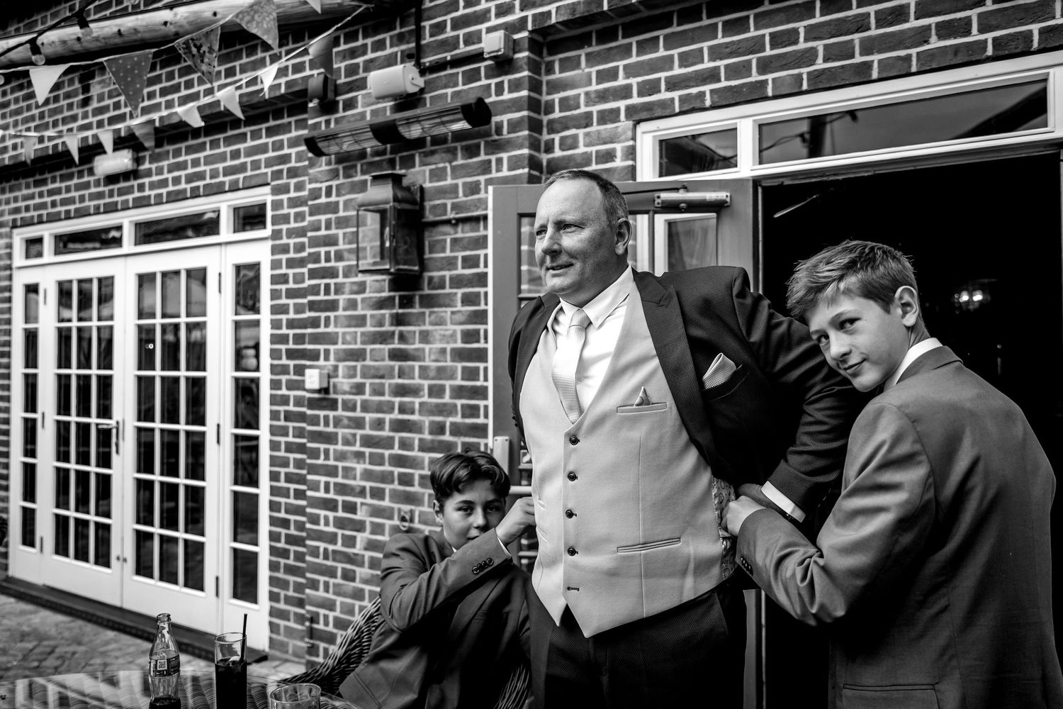 Black and white photo of people standing outside a brick building with French doors.