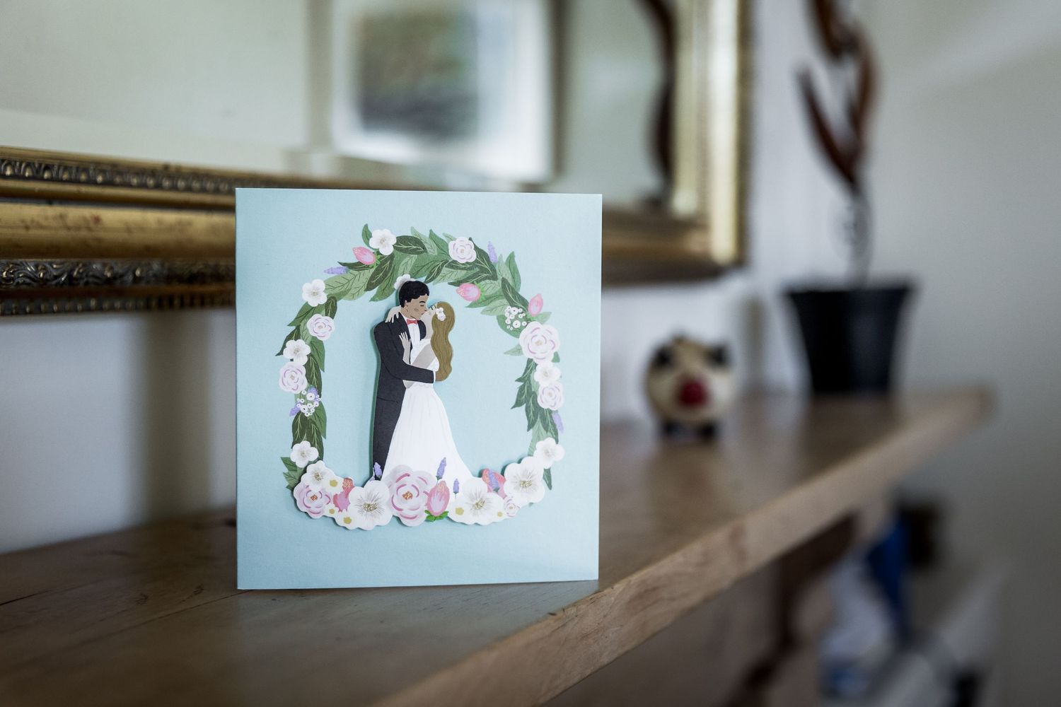 Close-up detail shot of delicate floral arrangements and decorative frames on a wooden surface.