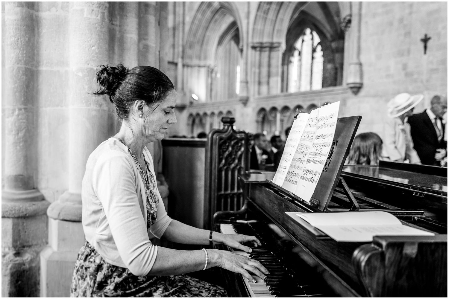 Black and white photo of musicians playing piano during a church ceremony.