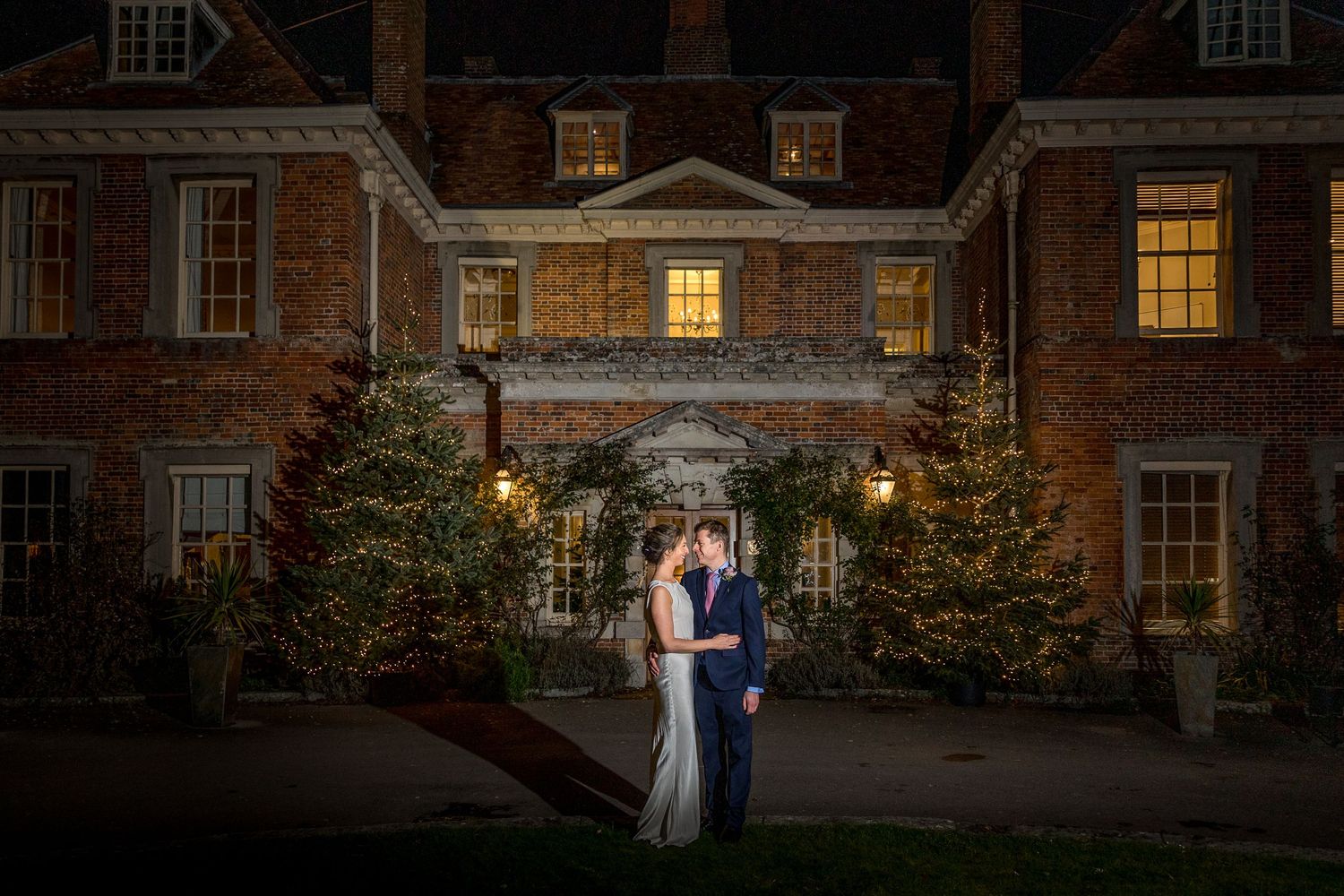Evening exterior shot of an illuminated historic brick building with glowing windows.