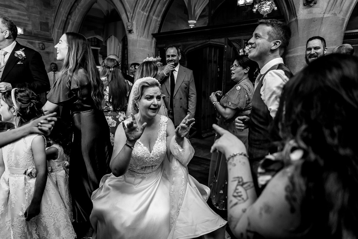 Wedding celebration candid moments captured in black and white under gothic arches.