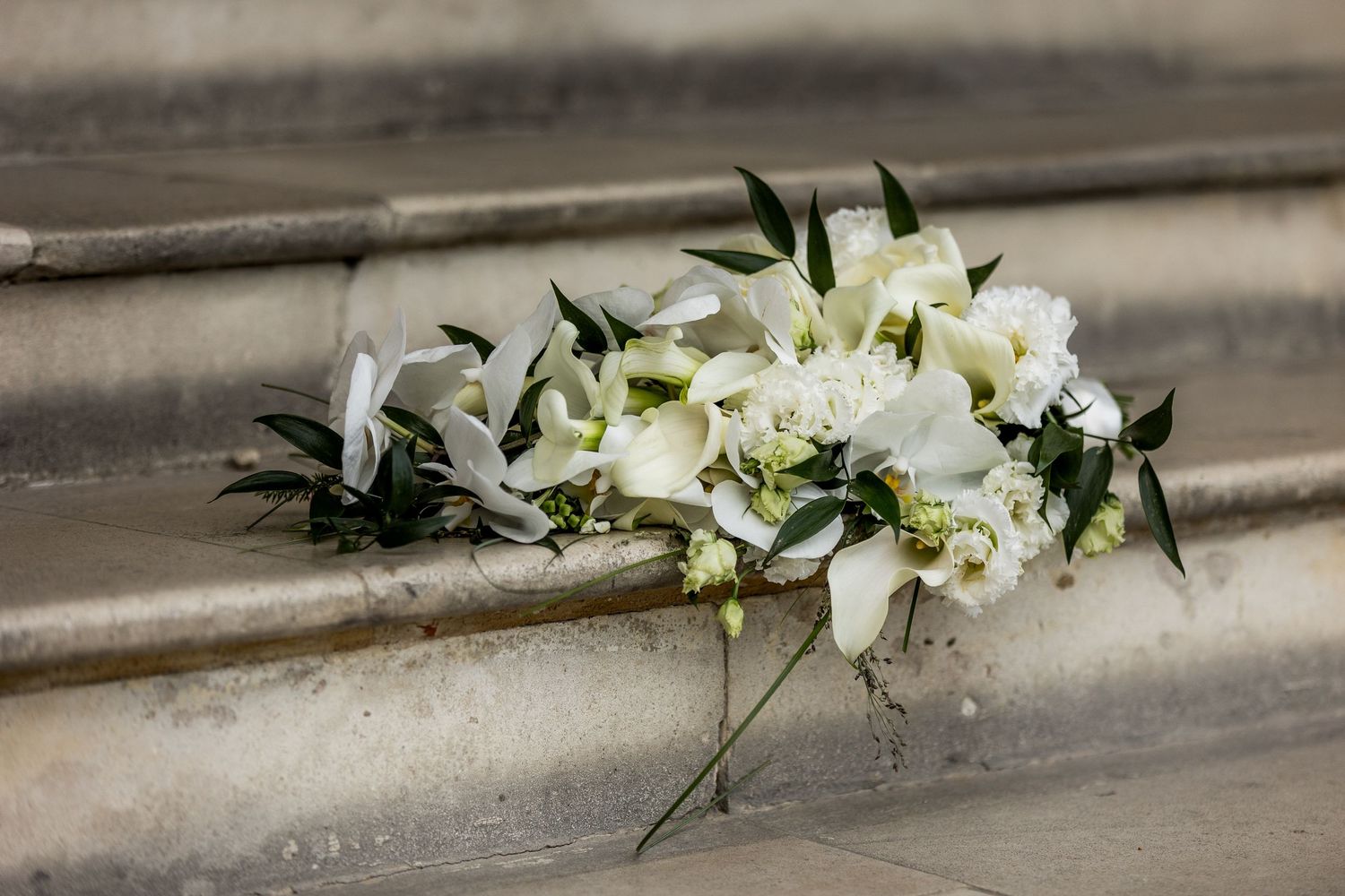 White floral arrangements elegantly displayed along a stone ledge in a row.