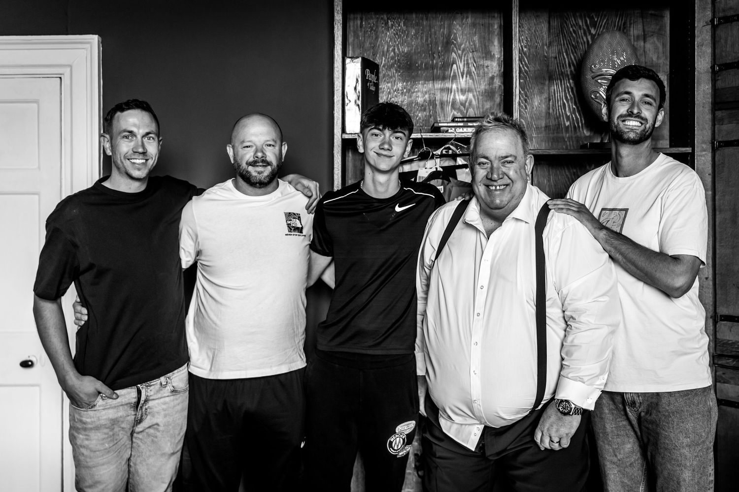 Black and white group photo of five people standing together indoors.