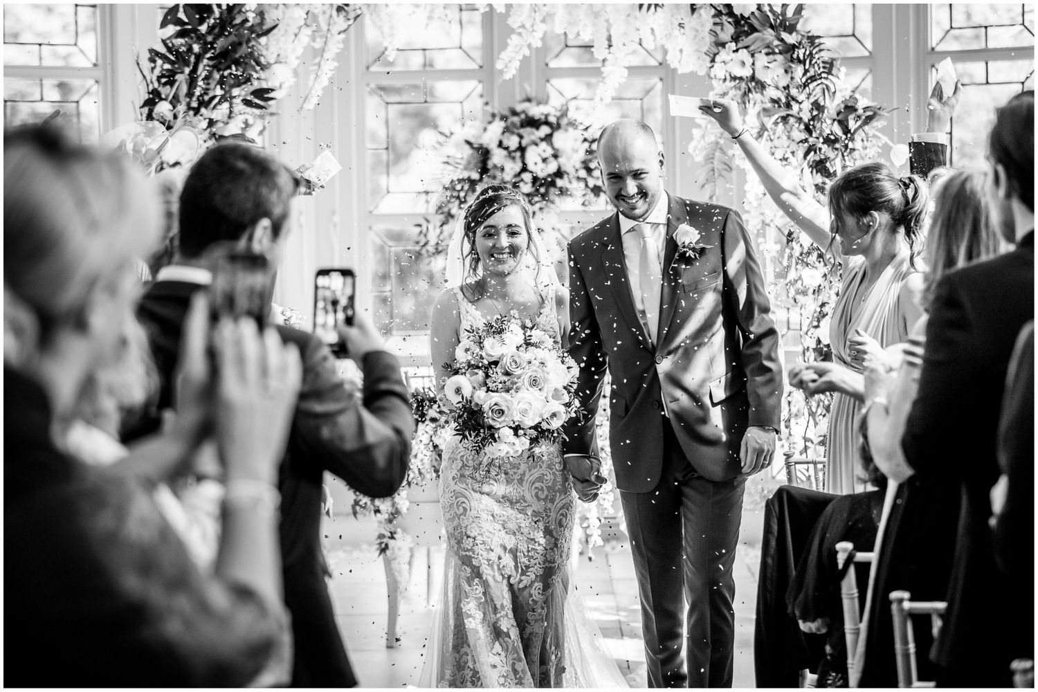 Wedding ceremony moments captured in a bright indoor venue with decorative floral arrangements.