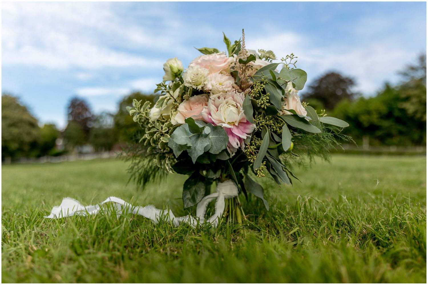 Fresh floral bouquets lay scattered on lush green grass in a garden setting.