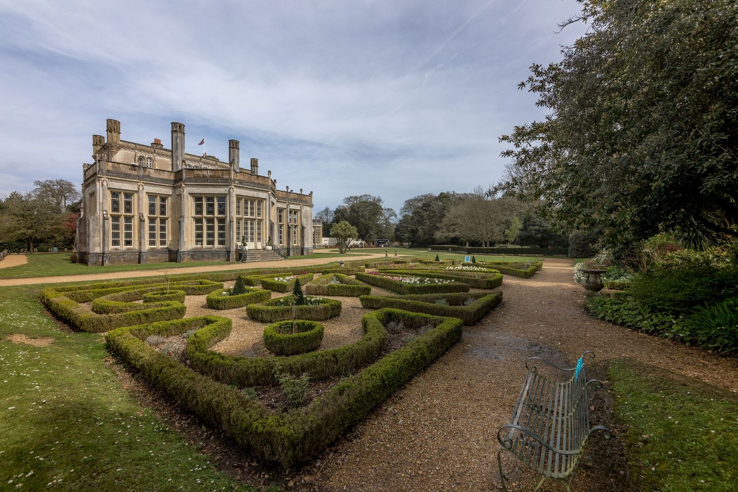 Panoramic view of formal gardens with manicured hedges and pathways leading to historic mansion.