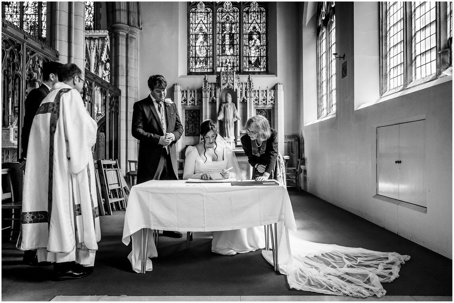 Black and white image of a wedding document signing ceremony in a church.