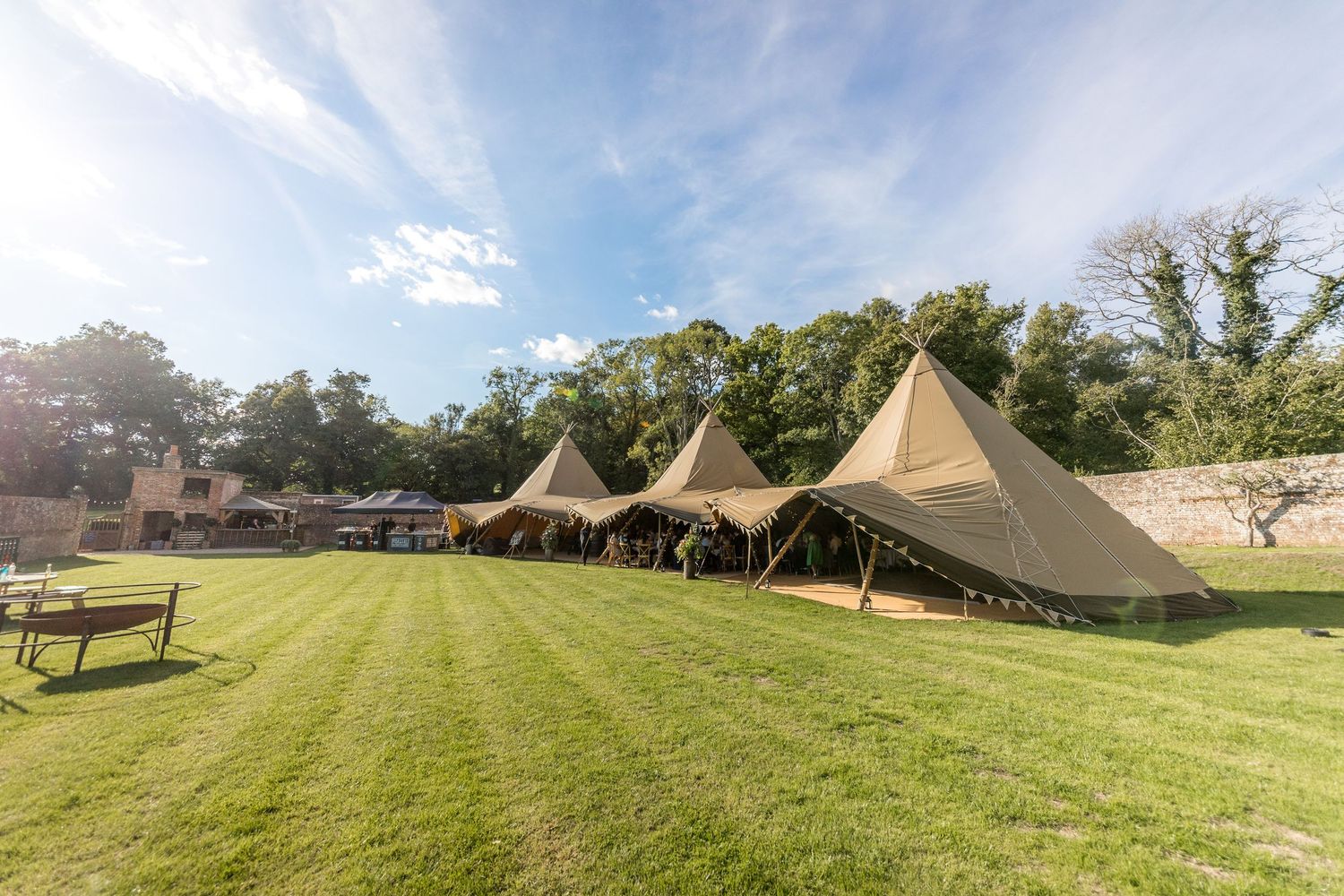 Scenic landscape view of wedding tents set up in a rolling green field on a sunny day.