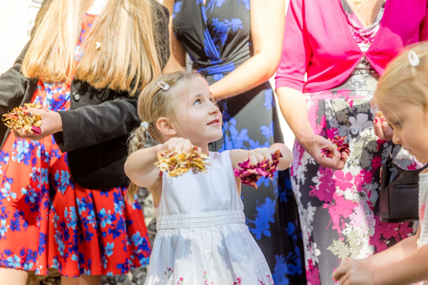 Wedding guests in colorful summer dresses celebrating at outdoor reception.