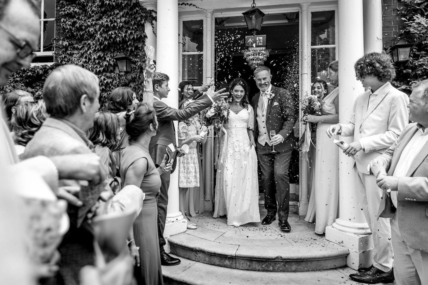 Black and white photo of wedding guests gathered outside columned entrance.